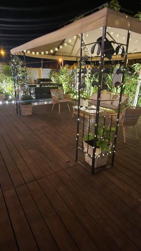 a deck with tables and chairs under a tent at בוס-תן בגולן in Giv'at Yo'av
