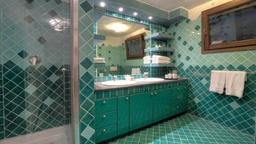 a green tiled bathroom with a sink and a shower at Villa Astra fronte mare - Porto Cervo in Porto Cervo