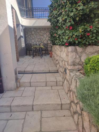 a stone wall with a table and chairs on a patio at Biuk Apartments in Novi Vinodolski