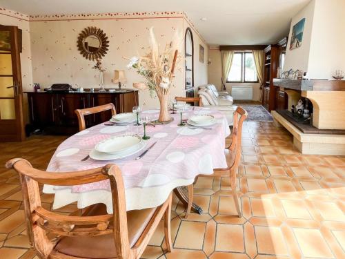 une table à manger avec des chaises et un tissu de table rose dans l'établissement Jolie maison avec jardin - quartier la Roulière - 4 personnes, à Givrand
