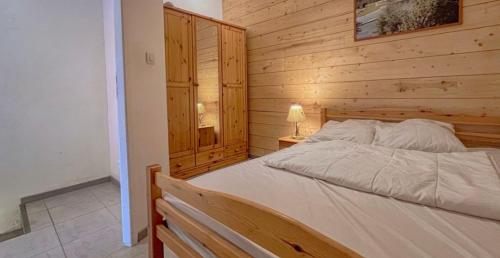 - une chambre avec un lit et un mur en bois dans l'établissement Logement 7pers-15mn Piste-Exposé Sud-Cœur station, à Aillon-le-Jeune