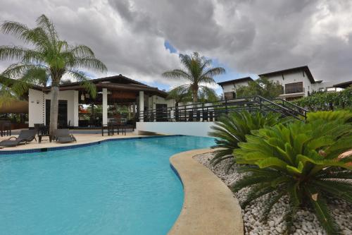 a swimming pool in front of a house with palm trees at Sybaris Suites & Residences in Juan Dolio