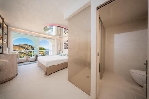 a bedroom with a bed and a bathroom at Destino Five Ibiza - 5-Star Grand Luxe Resort in Talamanca