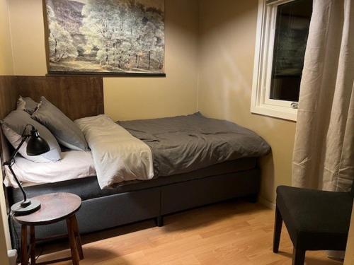a bedroom with a bed with a window and a chair at Sandskogen-Ystad in Ystad