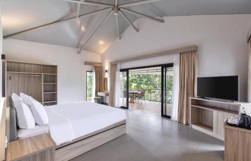 a bedroom with a bed and a flat screen tv at The Glamping at ARTOTEL Pelangi Park in Pasirkuda