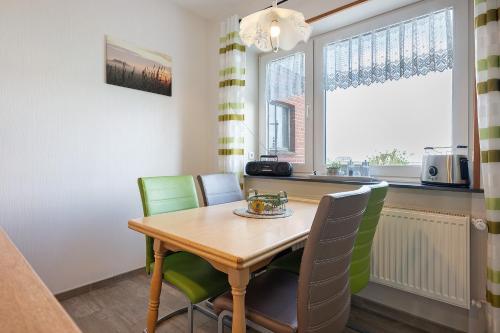 a dining room with a wooden table and green chairs at Gästehaus Tadenswarf in Tadenswarf