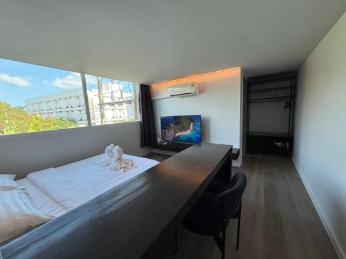 a bedroom with a bed with a desk and a large window at P168 Hostel Samui in Chaweng