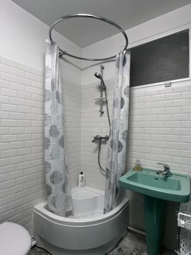 une salle de bain avec une baignoire, un lavabo et une douche dans l'établissement Les Trente Glorieuses, à Épône