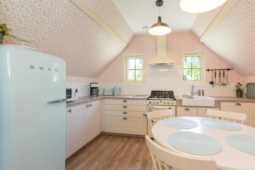 une cuisine avec une table et un réfrigérateur blanc dans l'établissement Gite Cottage de la Douloustre, à Montgaillard