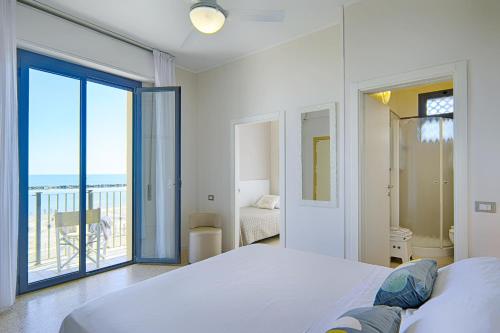 Un dormitorio blanco con una cama y un balcón. en Hotel Deanna, en Bellaria-Igea Marina