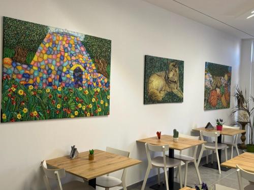 a row of tables in a restaurant with paintings on the wall at Dear Mary, B&B romantico vicino Lecce nel cuore del Salento in San Cesario di Lecce