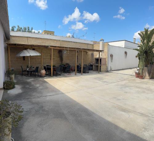 a building with a patio with tables and an umbrella at Dear Mary, B&B romantico vicino Lecce nel cuore del Salento in San Cesario di Lecce