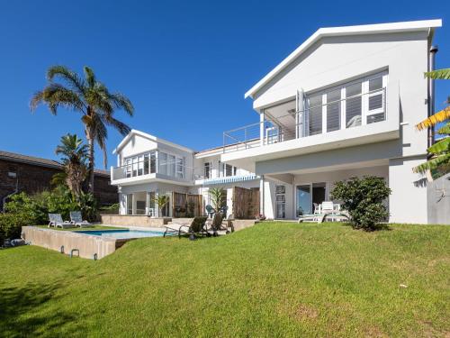 a large white house with a yard with a swimming pool at Berg n Sea in Plettenberg Bay
