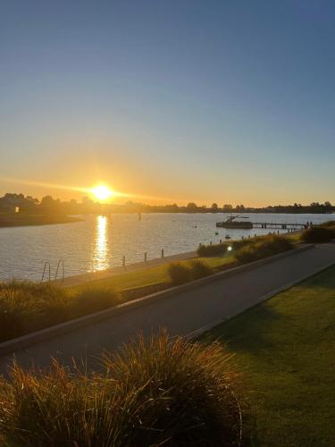 a sunset over a body of water with a road at Yarrawonga Golf & Lake Getaway in Yarrawonga