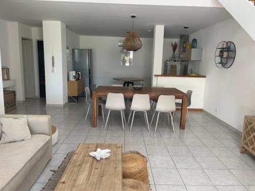 un salon avec une table en bois et des chaises blanches dans l'établissement Capra Scorsa, Maison avec spa privatif face plage Lozari, Ile Rousse, à Belgodère