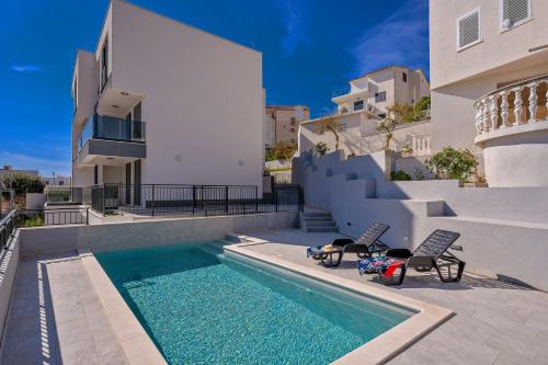 una piscina con dos sillas y una casa en Apartments 5 Stars Lux XYZ, en Rogoznica