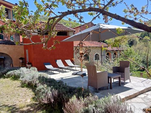 a patio with a table and chairs and an umbrella at Camerana La Casa Rossa in Camerana 