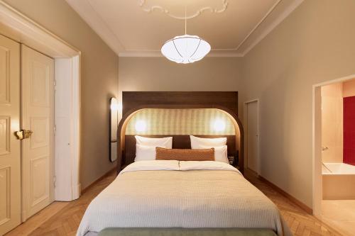 a bedroom with a large bed and a chandelier at Hotel Palais Mailberger Hof in Vienna