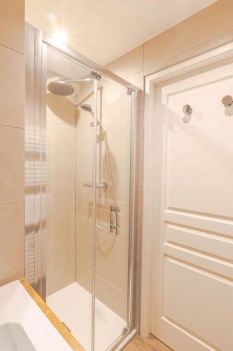 une douche avec une porte vitrée dans une salle de bain dans l'établissement Cassiopee, spacieux et familiale 3 chambres, à Annecy