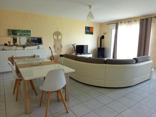 a living room with a couch and a table at Maison moderne 5 lits 8 personnes in Caudrot
