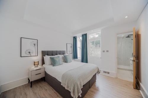 a white bedroom with a large bed with blue pillows at Kensington Prime Apartments in London