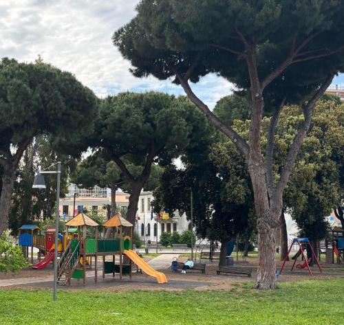 a playground with a slide in a park with trees at Alloggio al binario 9 e tre quarti in Civitavecchia
