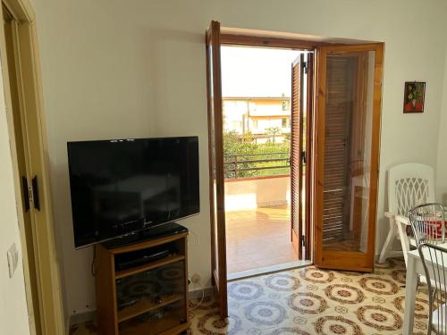 a living room with a flat screen tv and a balcony at Appartamento Complesso Maresol in Falerna Marina