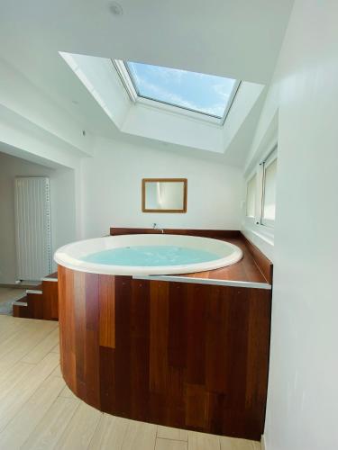 a bathroom with a bath tub with a skylight at Kerannette - Spa - Plage et centre ville in Perros-Guirec