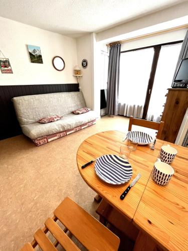 un salon avec une table en bois et un canapé dans l'établissement Au pied des pistes studio et jardin au soleil, à Montgenèvre