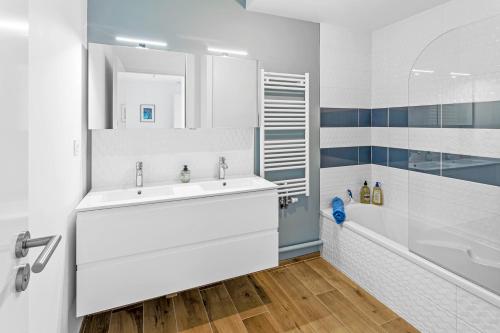 a bathroom with a white sink and a tub at Jardin du 8e Ciel - Neuf & Central in Nantes