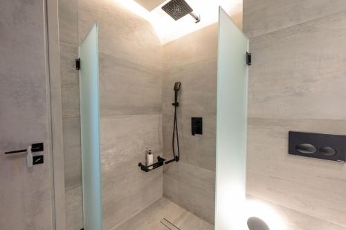 a shower with a glass door in a bathroom at Grand Kourouta Pool Apartments in Kourouta