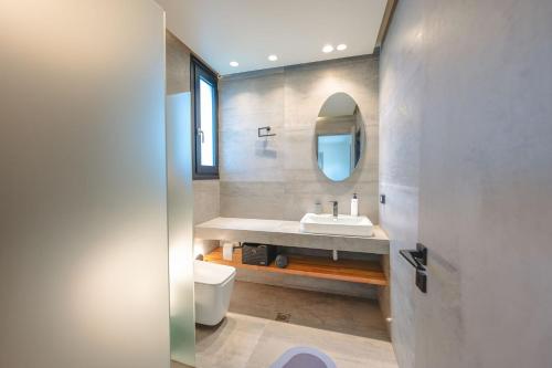 a bathroom with a sink and a toilet and a mirror at Grand Kourouta Pool Apartments in Kourouta