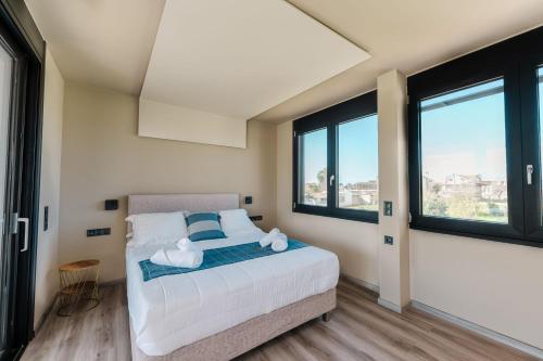 a bedroom with a bed and two windows at Grand Kourouta Pool Apartments in Kourouta