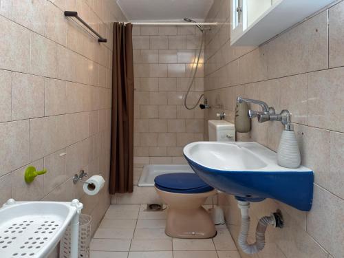 a bathroom with a blue sink and a toilet at CERES APARTMENTS free parking, kitchen & wi-fi in Utjeha