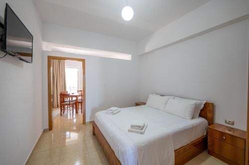 a bedroom with a white bed and a television at Aleksander ApartHotel in Ksamil