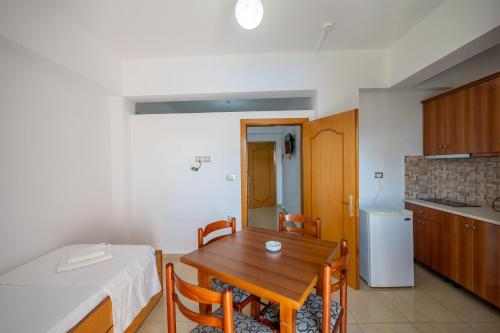 a kitchen and dining room with a wooden table and chairs at Aleksander ApartHotel in Ksamil