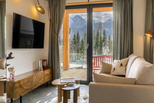 a living room with a couch and a large window at TatryTop Domy Manowce z jacuzzi in Kościelisko