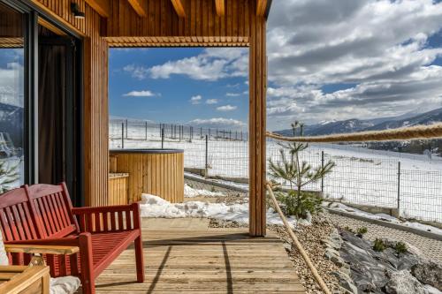 a porch with a bench and a view of the snow at TatryTop Domy Manowce z jacuzzi in Kościelisko