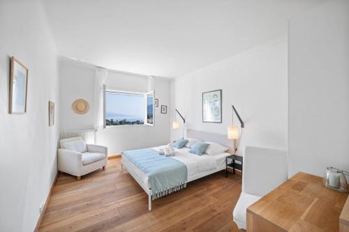 a white bedroom with a bed and a chair at Villa Shangrila, charming house with sea view, swimming pool and garden nr Monaco and Italy in Roquebrune-Cap-Martin