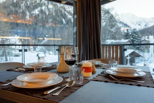 a table with plates and wine glasses and a window at Lillaz Home - Apartments in Cogne