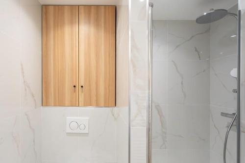 La salle de bains est pourvue d'une douche et d'une armoire en bois. dans l'établissement #45 Quiet chic 5mins walk to port and beach AC Wifi, à Villefranche-sur-Mer