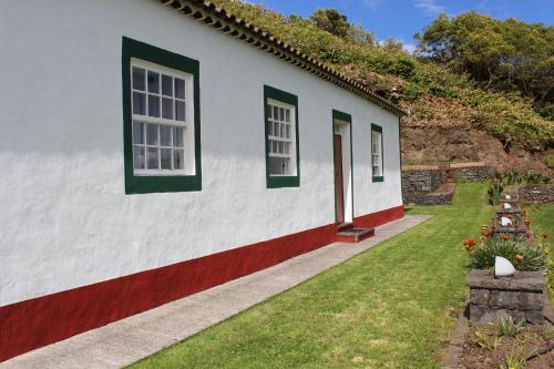 une maison blanche avec des fenêtres vertes et une cour dans l'établissement Casa da Avó - Turismo Rural, à Santo Espírito