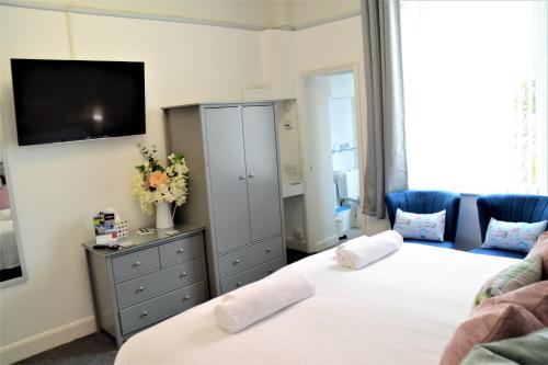 a bedroom with two beds and a tv on the wall at St Edmunds Guest House in Paignton