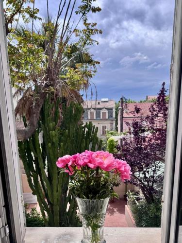 un vase rempli de fleurs roses dans une fenêtre dans l'établissement Le Mourillon Grand appartement proche des plages, à Toulon