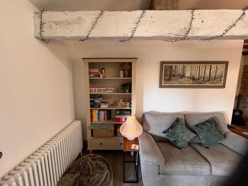 a living room with a couch and a book shelf at Tanyard Barn - Luxury Hot Tub & Secure Dog Field Included in Old Glossop