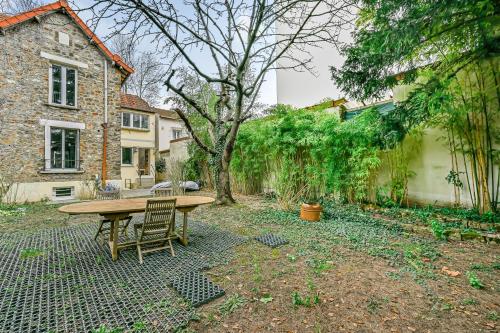 d'une terrasse avec une table et des chaises en bois dans la cour. dans l'établissement Le Chic - Chambre cosy aux portes de Paris, à Bagneux