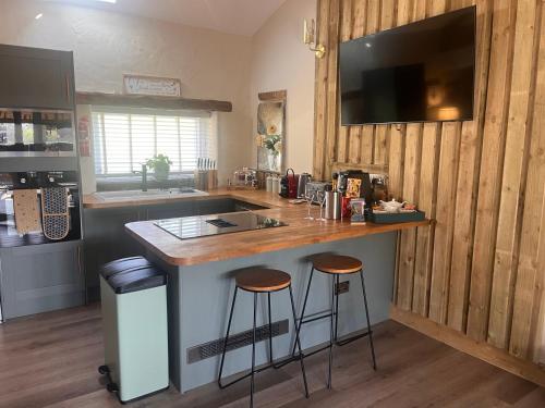a kitchen with a counter and stools at a island at Tanyard Barn - Luxury Hot Tub & Secure Dog Field Included in Old Glossop