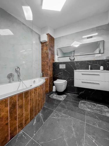 a bathroom with a tub and a toilet and a sink at L&C-Elbresidenzen & Suites am Elberadweg in Magdeburg