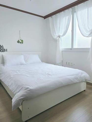 a white bed in a bedroom with a window at 머물다 울산 울산공항 5분 태화강역10분 울산 병영성 in Ulsan