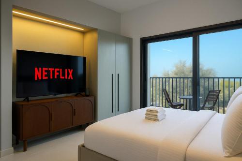 ドバイにあるSleek New Studio in Meydan, Fully Equipped and Spaciousのベッドルーム(ベッド1台、テレビ、バルコニー付)